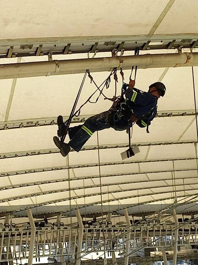 Técnico IRATA em acesso por corda sob a cobertura metálica do Maracanã